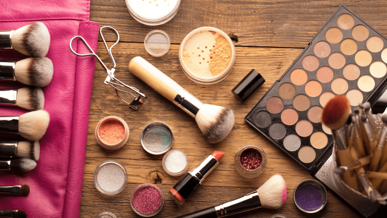 Beauty essentials and a pink pouch on wood.