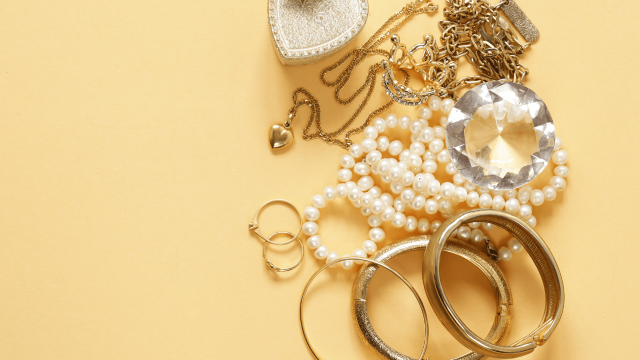 A warm flat lay of gold bangles, stones, and a crystal on cream.