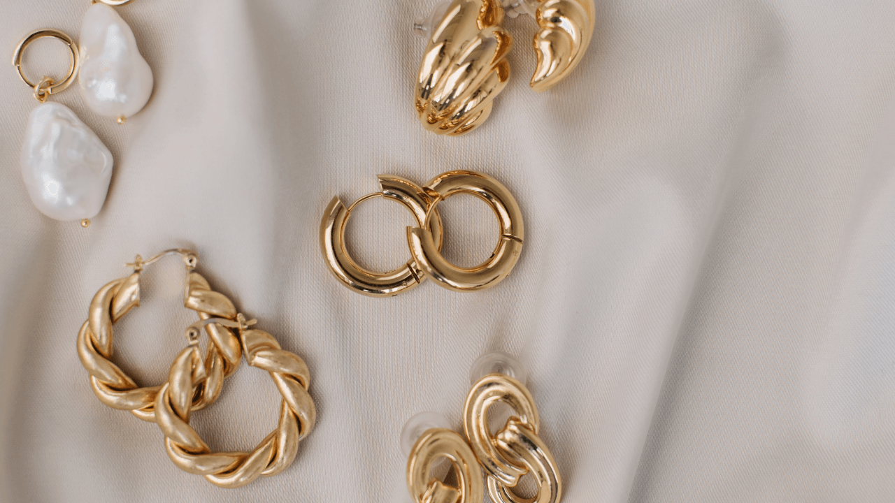 Gold hoop earrings and a baroque stone drop arranged on ivory silk.