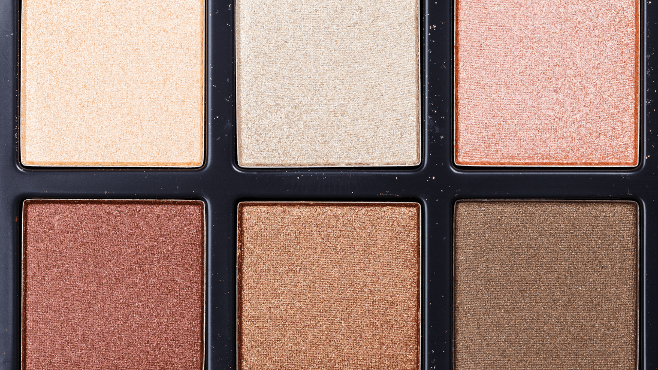 Macro of a warm shimmer eyeshadow palette in champagne and bronze tones.
